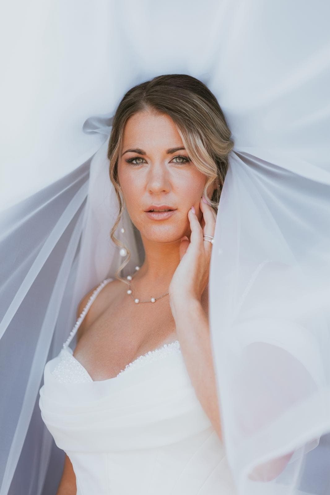 Mariée en peignoir avant la cérémonie, chignon bas et mèches ondulées
